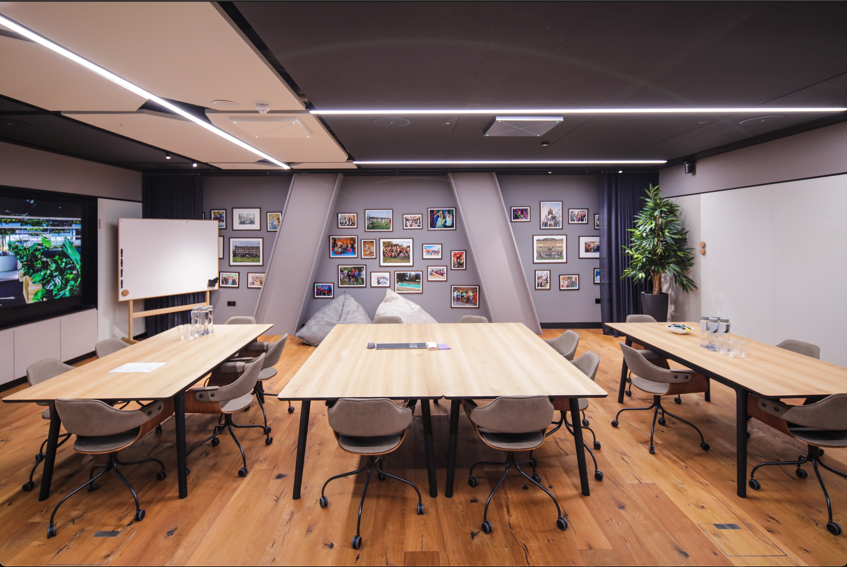 Room with big tables, beanbags, whiteboard and multiple photos hanging on the back wall