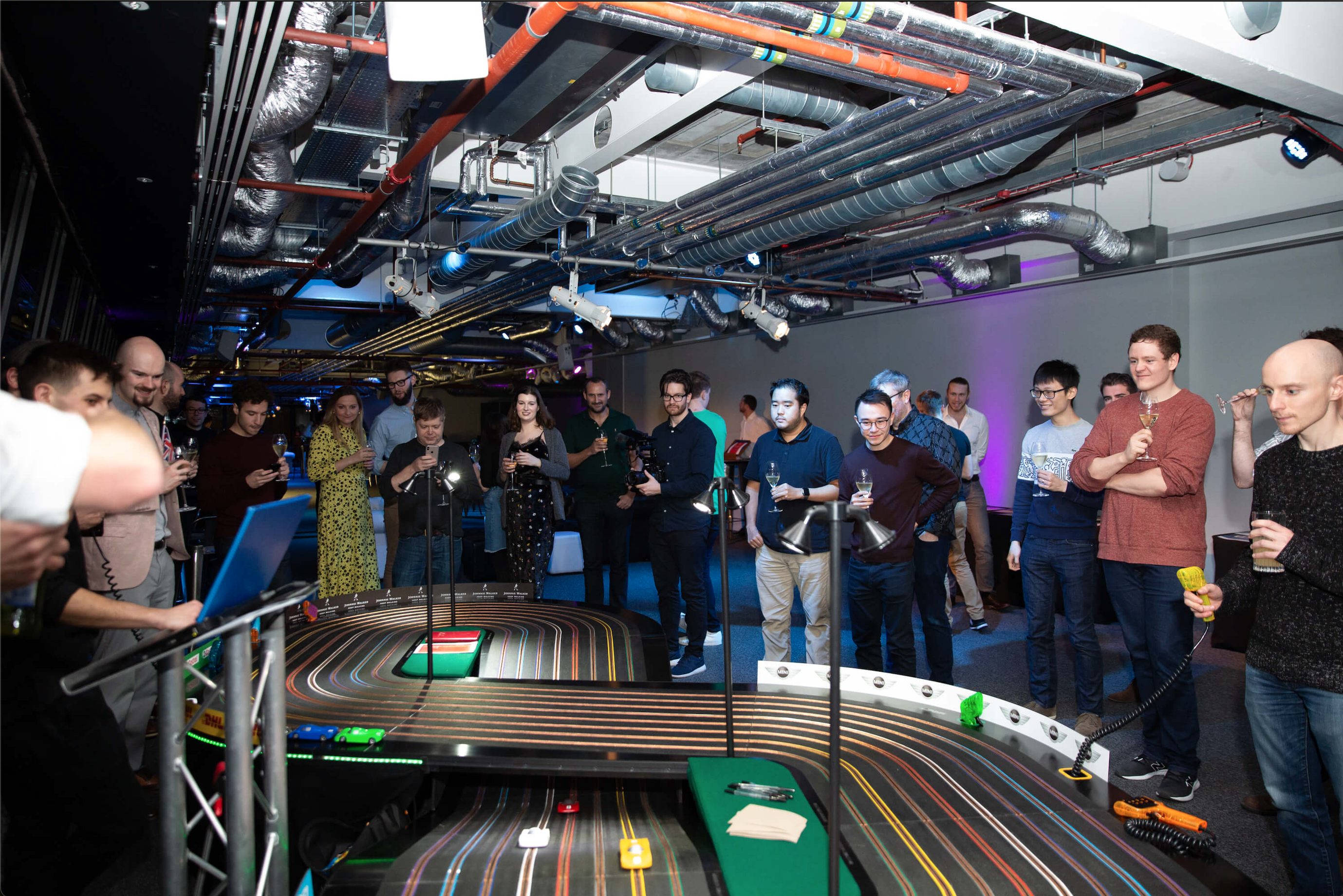 Extra large scalextric being playing by Quadrature team whilst drinking champagne