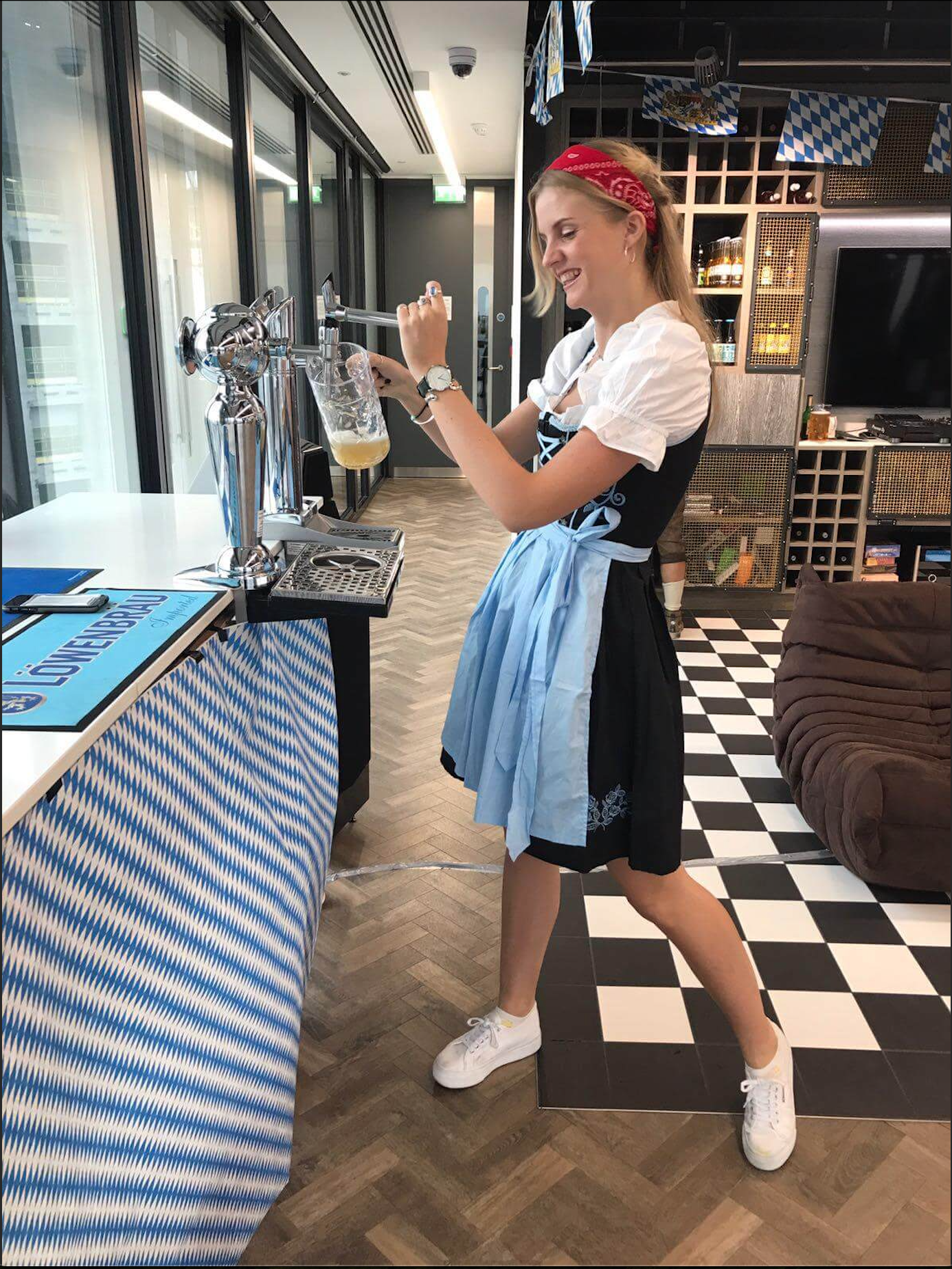 Lady smiling and pouring beer from a tap in a traditional German dress